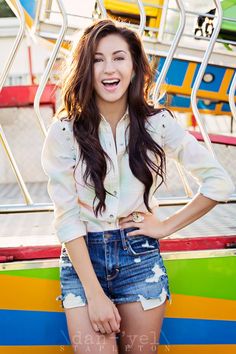 a young woman is posing in front of a carnival ride