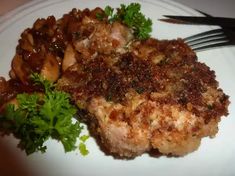 a white plate topped with meat and veggies next to a knife and fork