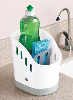 a white plastic container filled with bottles and sponges next to a green bottle in the holder