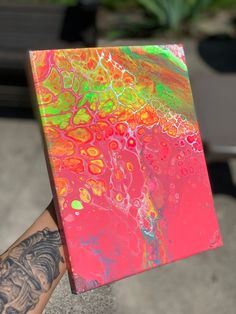 a person holding up a colorful piece of art