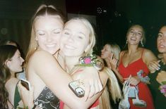 two young women hugging each other in front of many other girls at a party or gathering