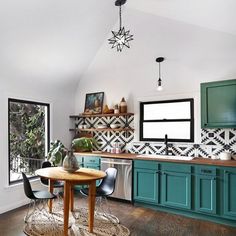 a kitchen with teal cabinets and wood flooring is seen in this image from the dining room