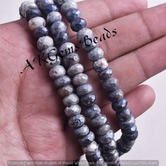 two strands of gray and white marble beads are held in someone's hand