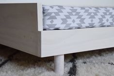 a close up of a wooden bed frame with a pillow on the bottom and side