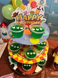 a birthday cake with green cupcakes and decorations on it at a children's birthday party