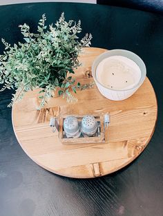 a wooden table topped with a plant and two salt shakers on top of it