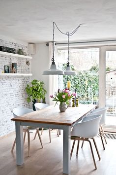 a dining room table with chairs and flowers in vases on the table next to it