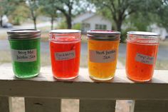 four jars filled with different colored liquid sitting on a porch