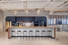 an empty kitchen with bar stools in the center and lots of lights hanging from the ceiling