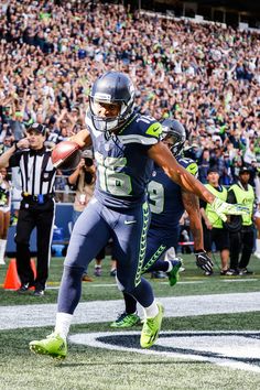 a football player running with the ball in his hand and people watching from the stands