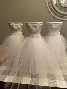 three bridesmaid dresses are lined up on a table in front of a clock