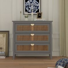 a gray dresser with wicker drawers and pictures on the wall