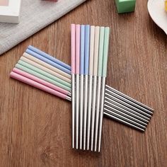 several different colored drinking straws on a wooden table next to fruit and candy bars