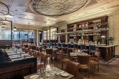 a restaurant with many tables and chairs in front of the bar, along with wine glasses on the table