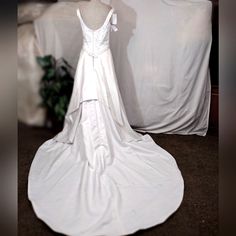 a white wedding dress on display in front of a chair