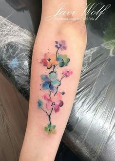 a watercolor style flower tattoo on the arm