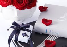 a bouquet of red roses sitting on top of a book next to a white vase