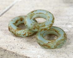 three rusted green donuts sitting on top of a stone slab next to each other