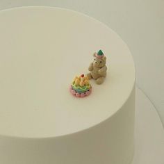 a white cake with a small teddy bear on top