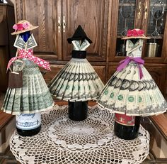 three mannequins made out of money sitting on top of a doily