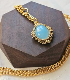 Vintage Gold Tone Necklace with blue simulated Chalcedony Gemstone Pendant featuring very pretty light yellow gold and sky blue combination.  The pendant is brass with resin stone. Looks real but I don't think it's genuine gemstone.  Necklace is made with 20 inches long chain with hook. Gold Chalcedony Jewelry As A Gift, Blue Oval Locket Necklace, Oval Blue Locket Necklace, Gold Necklaces With Large Stone In Oval Pendant, Gold Necklace With Large Oval Pendant Stone, Gold Necklace With Large Oval Stone Pendant, Handmade Gold Chalcedony Necklace, Gold Necklace With Large Round Pendant, Blue Brass Pendant Jewelry