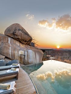 the sun is setting over an outdoor swimming pool with chaise lounges on it