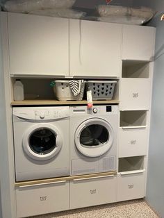 a washer and dryer in a room with cabinets on the wall behind them