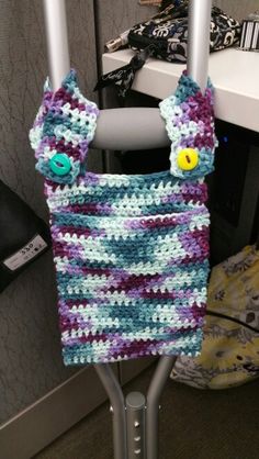 a crocheted bag hanging on a metal rack in front of a desk and chair