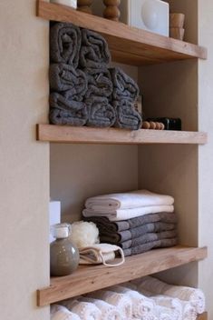 towels are stacked on wooden shelves in the bathroom