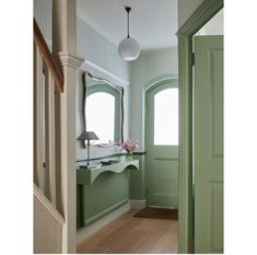 an image of a green room with a vanity and mirror on the door way to another room