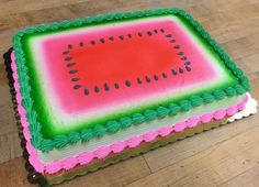 a watermelon cake with green and pink icing on a wooden table top