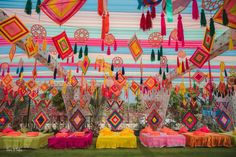 colorful decorations are hanging from the ceiling in an outdoor area with green grass and bright colors