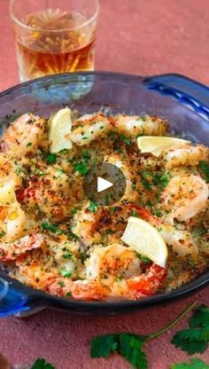 a pan filled with shrimp and garnish next to a glass of beer