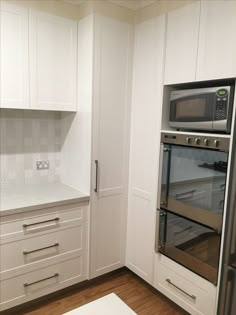 a kitchen with white cupboards and an oven in the center, along with wooden flooring