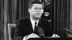 a man sitting at a desk with microphone in front of him