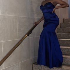 a woman in a blue dress standing on some stairs