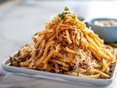 a pile of food sitting on top of a white plate next to a blue bowl