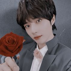 a man in a gray suit holding a red rose