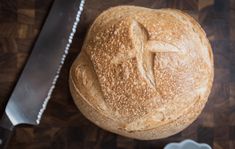 a loaf of bread sitting on top of a wooden cutting board next to a knife