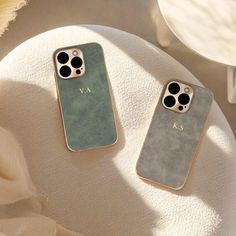 two iphone cases sitting next to each other on a white chair with a flower in the background