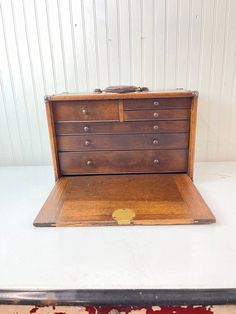 an old wooden chest sitting on top of a white table next to a red rug