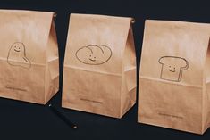 three brown paper bags with drawings on them