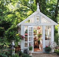 a small white house with lots of potted plants