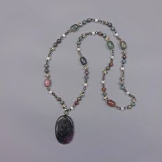 "Indian Agate Oval Necklace. A Large Natural High-Polished Oval Shaped Indian Agate Pendant That Reflects Multi-Color Tones in Brown, Dark Green, and Dark Grey Tones. It Connects to A Multi Gem Stone Necklace. Each Bead Is Hand-Knotted with Great Cord Strength. Necklace: 34\" L. Pendant: 1.50\" W x 2.25\" L. Clasp: NA Material: Indian agate/ocean jasper/dalmatian jasper/cultured fresh water pearl/hematite/crystal/no metal type Beaded/each bead is knotted" Hematite Crystal, Indian Agate, Oval Necklace, Lapis Lazuli Necklace, Dalmatian Jasper, Carnelian Beads, Crystal Chain, Fresh Water Pearl, Pearl Gemstone