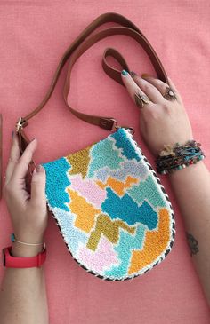 a woman holding a purse on top of a pink surface