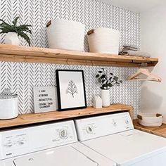 a washer and dryer are sitting on the shelves in this small laundry room