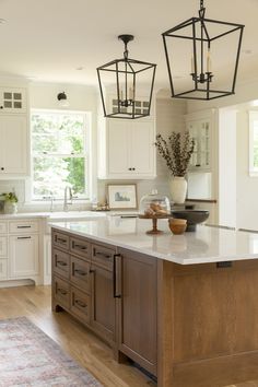 a large kitchen with an island in the middle and two lights hanging from the ceiling