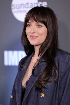 a woman with long dark hair wearing a blue blazer