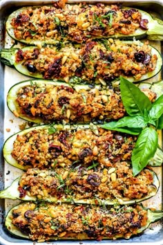 zucchini stuffed with meat and vegetables in a baking pan, garnished with fresh basil leaves