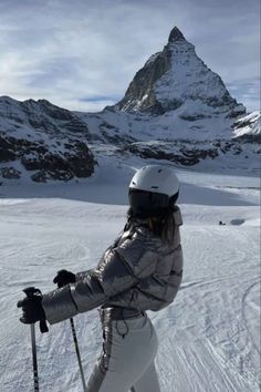 a woman on skis in the snow with mountains in the backgrouund